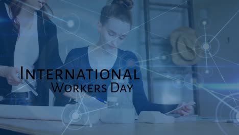 Animation-of-international-workers-day-text-over-caucasian-businesswomen-in-office