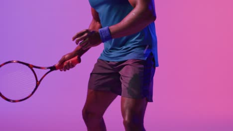 Video-of-midsection-of-african-american-male-tennis-player-bouncing-ball-in-neon-pink-lightning