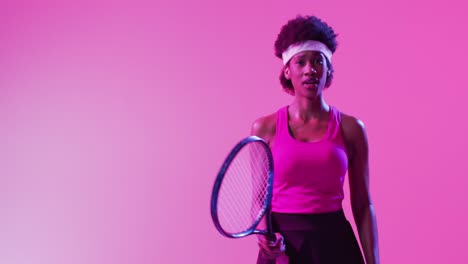 Video-of-focused-african-american-female-tennis-player-hitting-ball-on-neon-pink-lightning