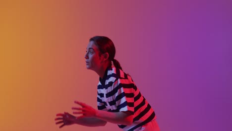 Happy-caucasian-female-rugby-player-catching-rugby-ball-over-neon-pink-lighting