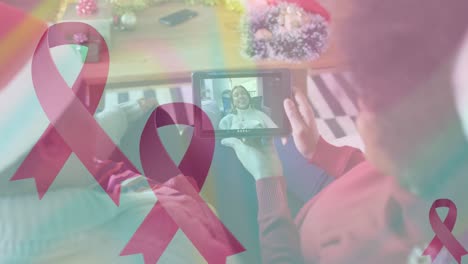 Animation-of-pink-ribbons-over-african-american-women-having-christmas-video-call