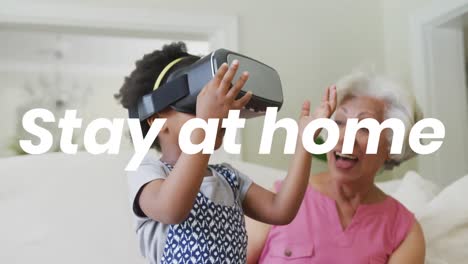 Animation-of-stay-at-home-text-over-african-american-grandmother-and-granddaughter-using-vr-headset