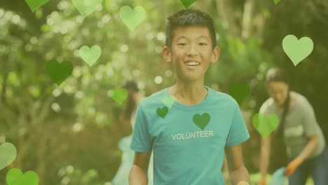 Animation-of-hearts-icons-over-asian-volunteers-segregating-waste