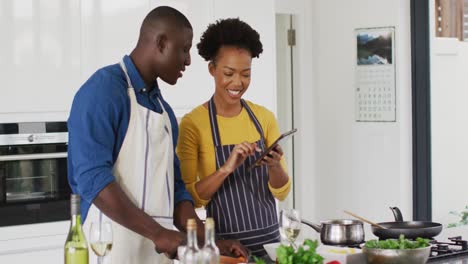 Video-Eines-Glücklichen-Afroamerikanischen-Paares,-Das-Zusammen-Mit-Einem-Tablet-Kocht