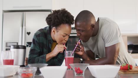 Video-Eines-Glücklichen-Afroamerikanischen-Paares,-Das-Hausgemachten-Saft-Aus-Einem-Glas-Mit-Strohhalmen-Trinkt