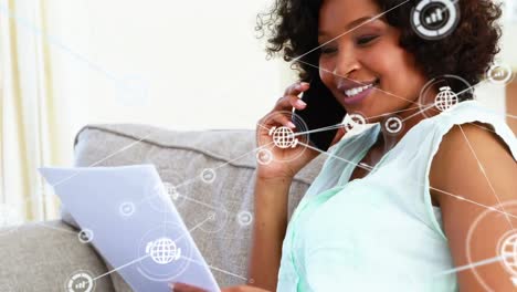 Animation-of-network-of-connections-with-icons-over-african-american-woman-talking-on-smartphone