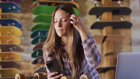 Video-Einer-Kaukasischen-Skateboarderin,-Die-Ihr-Smartphone-Im-Skateshop-Benutzt