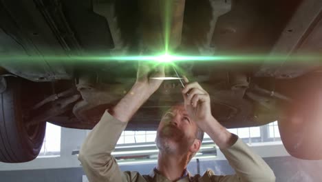 Animation-of-light-spots-over-caucasian-man-repairing-car