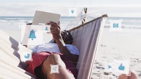 Animation-of-connections-over-relaxed-african-american-man-reading-book-in-hammock-on-beach