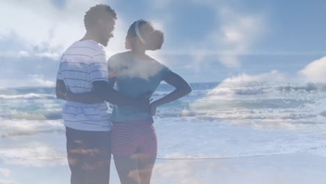 Animation-of-clouds-over-african-american-couple-at-beach