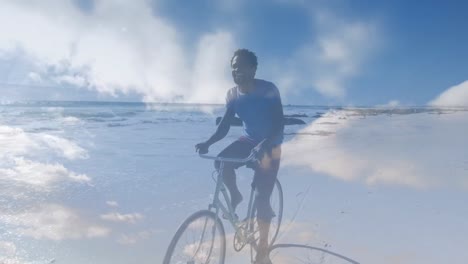 Animation-Von-Wolken-über-Einem-Glücklichen-Afroamerikanischen-Mann-Mit-Fahrrad-Am-Strand