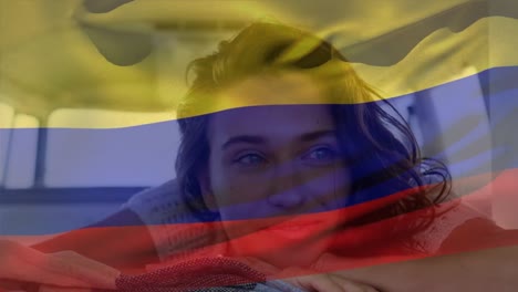 Animation-of-colombia-flag-waving-over-smiling-caucasian-woman-sitting-in-backseat-of-pick-up-truck