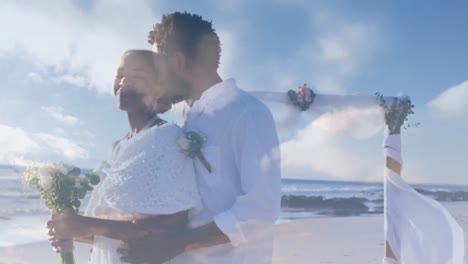 Animation-Eines-Glücklichen,-Frisch-Verheirateten-Afroamerikanischen-Paares-über-Wolken-Und-Meereslandschaft