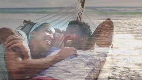 Animation-of-happy-african-american-couple-in-hammock-on-beach-over-seascape