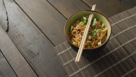 Composition-of-bowl-of-pad-thai-with-chopsticks-on-wooden-background