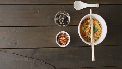 Composition-of-bowl-of-pad-thai-with-soy-sauce-and-chopsticks-on-wooden-background