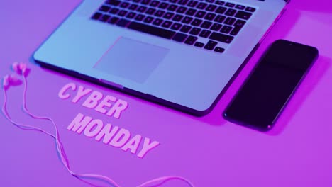 Composition-of-laptop,-earphones-and-smartphone-with-cyber-monday-text-on-purple-background