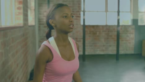 Animation-Von-Lichtflecken-über-Einer-Afroamerikanischen-Frau,-Die-Im-Fitnessstudio-Gewichte-Hebt