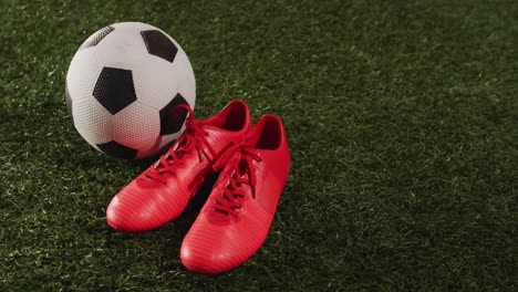 Animation-of-football-and-red-shoes-over-grass-with-copy-space