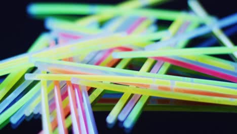 Animation-of-multiple-colorful-neon-glow-sticks-over-black-background
