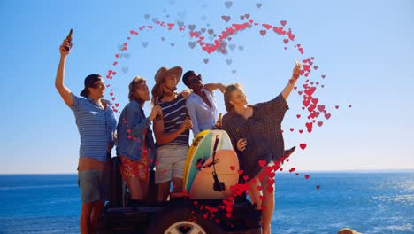 Animation-of-hearts-forming-heart-shape-over-multiracial-friends-taking-selfie-against-sea-and-sky