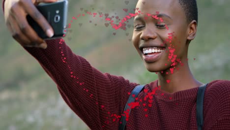 Animation-of-heart-over-happy-african-american-woman-taking-selfie