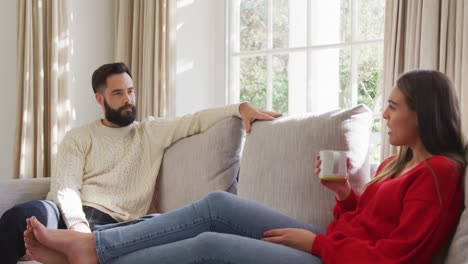 Video-of-happy-caucasian-couple-siting-on-sofa-and-drinking-coffee