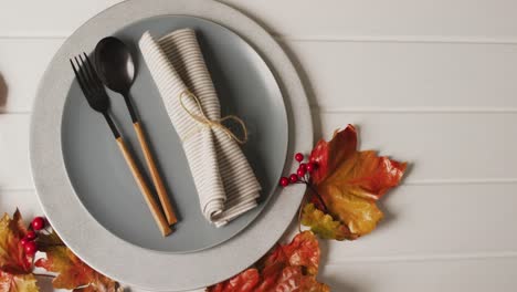 Video-of-plate-with-cutlery-and-autumn-decoration-with-leaves-on-white-surface