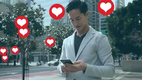 Animation-of-heart-shapes-floating-over-biracial-businessman-using-smartphone-while-standing-on-road