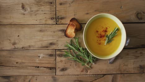 Video-of-cream-vegetable-soup-in-bowl-on-wooden-table-with-rosemary