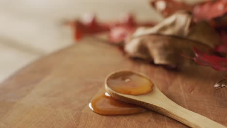 Video-of-maple-syrup-on-wooden-spoon-and-board-with-autumn-leaves