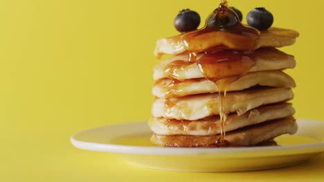 Video-of-maple-syrup-pouring-into-pancakes-on-yellow-background
