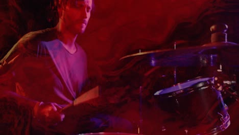Animation-of-glowing-red-lights-over-mid-section-of-caucasian-man-playing-drums