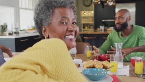 Video-Einer-Glücklichen-Afroamerikanischen-Großmutter,-Die-Sich-Am-Frühstückstisch-Der-Familie-Umdreht-Und-Lächelt