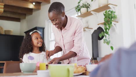 Video-Einer-Glücklichen-Afroamerikanischen-Mutter,-Die-Am-Familienfrühstückstisch-Brot-Für-Ihre-Tochter-Buttert