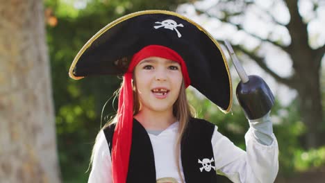Video-of-happy-caucasian-girl-in-pirate-costume-holding-halloween-trick-or-treat-basket-in-garden