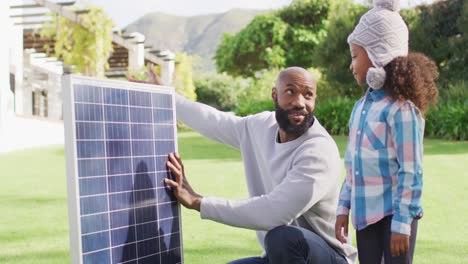 Video-Eines-Glücklichen-Afroamerikanischen-Vaters,-Der-Seiner-Tochter-Im-Sonnigen-Garten-Das-Solarpanel-Erklärt