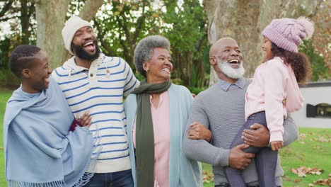 Video-portrait-of-happy-african-american-parents-with-grandparents-holding-granddaughter-in-garden