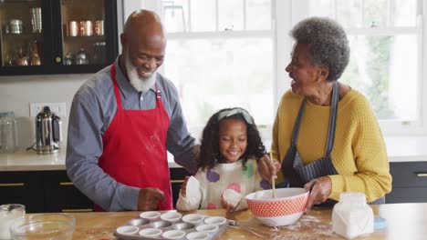 Video-Einer-Glücklichen-Afroamerikanischen-Enkelin,-Die-Mit-Den-Großeltern-In-Der-Küche-Kuchen-Backt