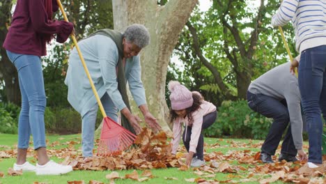 Video-of-happy-african-american-parents-and-daughter-collecting-leaves-with-grandparents-in-garden
