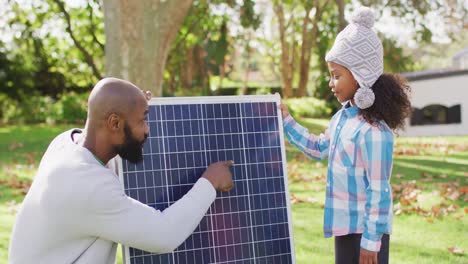 Video-Eines-Glücklichen-Afroamerikanischen-Vaters,-Der-Seiner-Tochter-Im-Herbstgarten-Das-Solarpanel-Erklärt