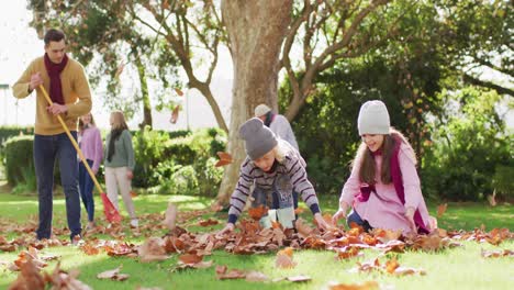 Video-of-happy-caucasian-son-and-daughter-throwing-autumn-leaves-while-father-rakes-them-up