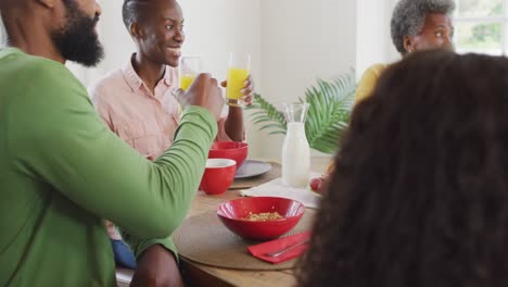Video-Von-Glücklichen-Afroamerikanischen-Eltern,-Töchtern-Und-Großeltern,-Die-Am-Esstisch-Anstoßen