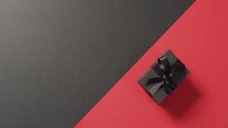 Overhead-view-of-black-gift-box-black-ribbon-on-black-and-red-background-with-copy-space