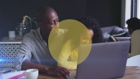 Animation-Gelber-Kreise-über-Einem-Afroamerikanischen-Mann-Und-Seiner-Tochter,-Die-Gemeinsam-Einen-Laptop-Benutzen