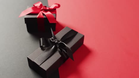 Two-black-gift-boxes-with-red-and-black-ribbons-on-black-and-red-background-with-copy-space