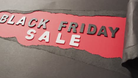 Ripped-black-paper-with-black-friday-sale-text-in-black-and-white-on-red-background