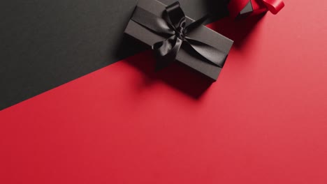 Overhead-view-of-two-black-gift-boxes-with-red-and-black-ribbons-on-black-and-red-with-copy-space