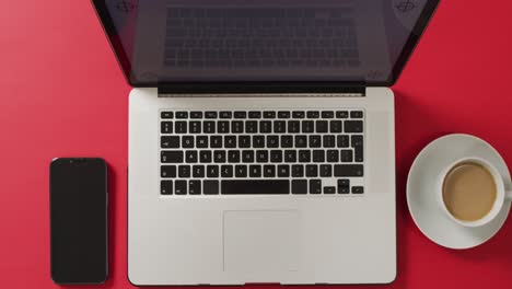 Draufsicht-Auf-Laptop-Mit-Smartphone-Und-Kaffee-Auf-Rotem-Schreibtisch