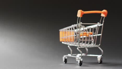 Empty-shopping-trolley-on-seamless,-lit-black-background-with-copy-space